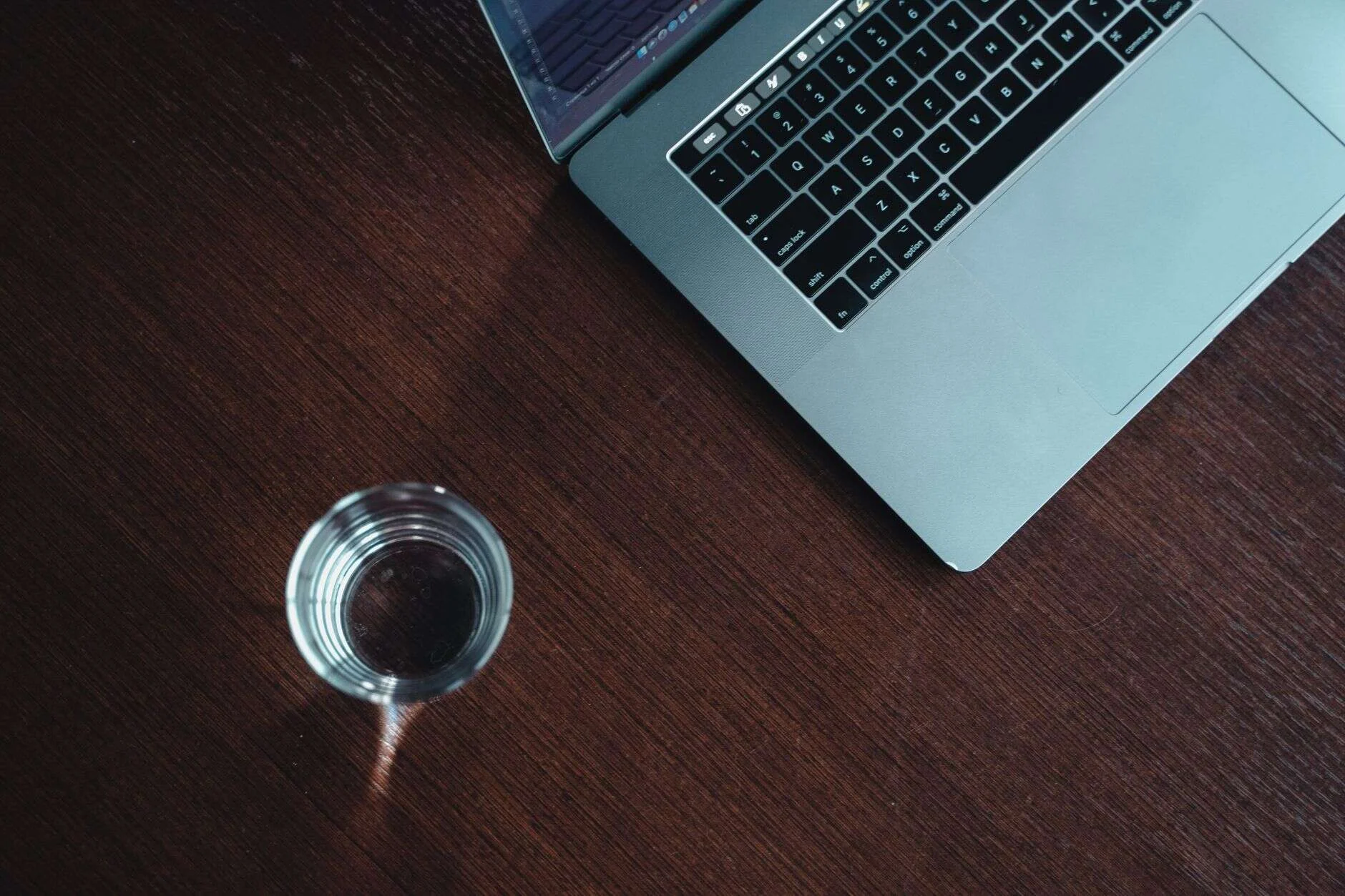 Portátil junto a un vaso de agua, riesgo de MacBook Air mojado